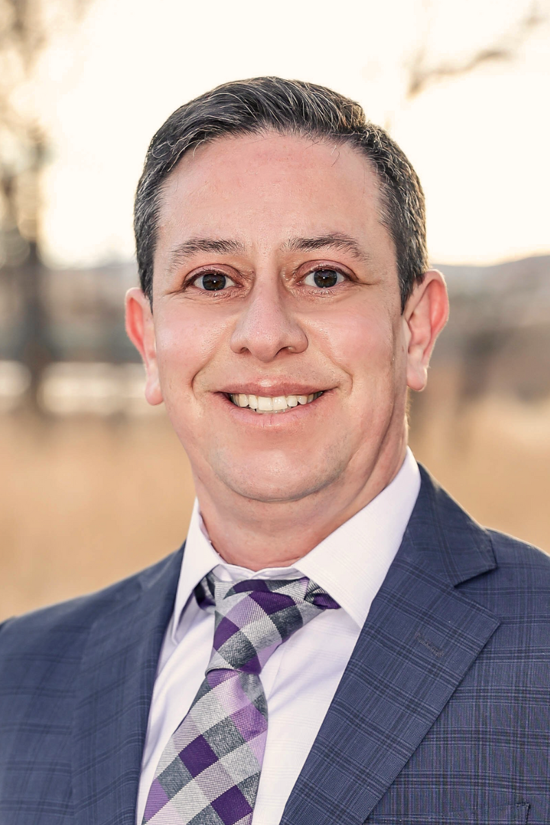 Photo of Kris Campbell wearing a suit and purple tie.